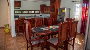 Un comedor con una mesa y sillas de madera, una cocina con armarios de madera, un refrigerador y un microondas.
