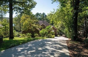 Set amidst mature trees, this traditional home features a main house with a gabled roof and a smaller attached structure.