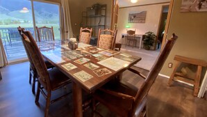 A dining area with a large wooden table, six chairs, and a view of a patio with chairs.