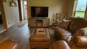 A living room with a leather sofa, a wooden entertainment unit with a TV, and a fireplace.