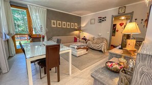 A cozy living room with a dining area, a sofa, a coffee table, and a lamp.