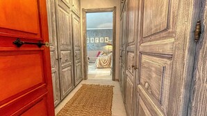 Ein Flur mit Holztüren, die zu einem Raum mit einem gestreiften Sofa und einer Decke führen.