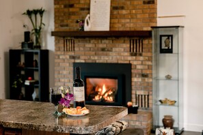Cozy living area with a fireplace, wine, and fresh fruit.