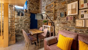 A rustic interior with a stone wall, wooden furniture, and a cozy seating area. - Contemporary styled studio (Piódão)