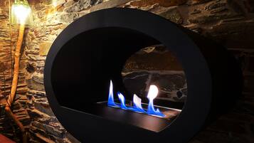 Una chimenea circular con llamas visibles, frente a una pared de piedra.