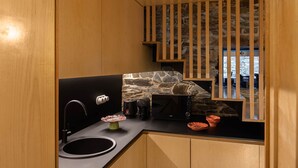 A compact kitchen with a stone backsplash, a coffee machine, and a microwave. - Contemporary styled studio (Piódão)