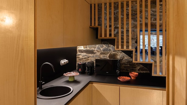 A compact kitchen with a stone backsplash, a coffee machine, and a microwave.