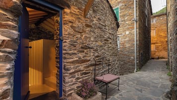 A stone building with a wooden door, a bench, and a stone pathway.