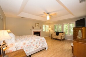 A bedroom with a bed, a fireplace, a sofa, and a television.