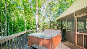 Een hottub op een houten terras, omringd door bomen.