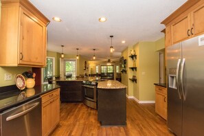 A modern kitchen with wooden cabinets, stainless steel appliances, and a central island.