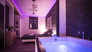 A modern bedroom with a large bed, a small desk, a window, and a bathtub. - LE CHALET ZEN LOVE (Foucherans)