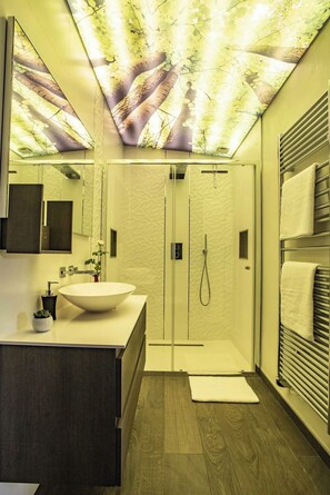 A modern bathroom with a large mirror, a white sink, a walk-in shower, and a towel rack. - LE CHALET ZEN LOVE (Foucherans)