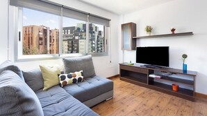 Un salon moderne avec un canapé gris, un téléviseur à écran plat et un meuble de rangement en bois.