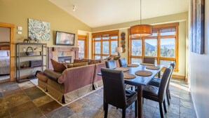 A spacious living room with a fireplace, a dining area with a large table and chairs, and a cozy seating area with a sofa. - Spacious Top-Floor 3-bed Springs Condo: 5 minute walk to gondola and restaurants (Keystone)