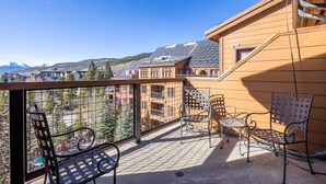 A balcony with metal chairs and a table, overlooking a residential area with houses and mountains. - Spacious Top-Floor 3-bed Springs Condo: 5 minute walk to gondola and restaurants (Keystone)