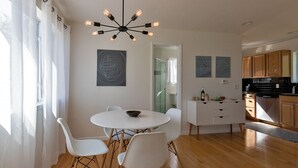 A modern kitchen with wooden cabinets, a white dining table with chairs, and a pendant light. - Peaceful River Retreat with Fireplace & Panoramic Views (Cementon)