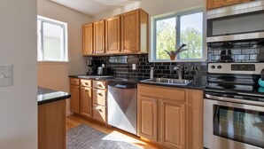 A modern kitchen with wooden cabinets, a stainless steel range, and a dishwasher. - Peaceful River Retreat with Fireplace & Panoramic Views (Cementon)