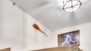 A bunk bed with a wooden frame and drawers, a ceiling light fixture, and a framed artwork on the wall. - Merlin's Bunkhouse at the Ore House Inn (New Castle)