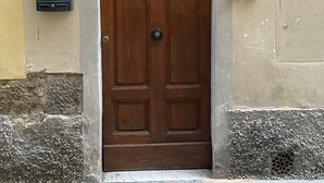 Una puerta de madera con un ventanuco de metal encima, un buzón y un timbre en la pared.