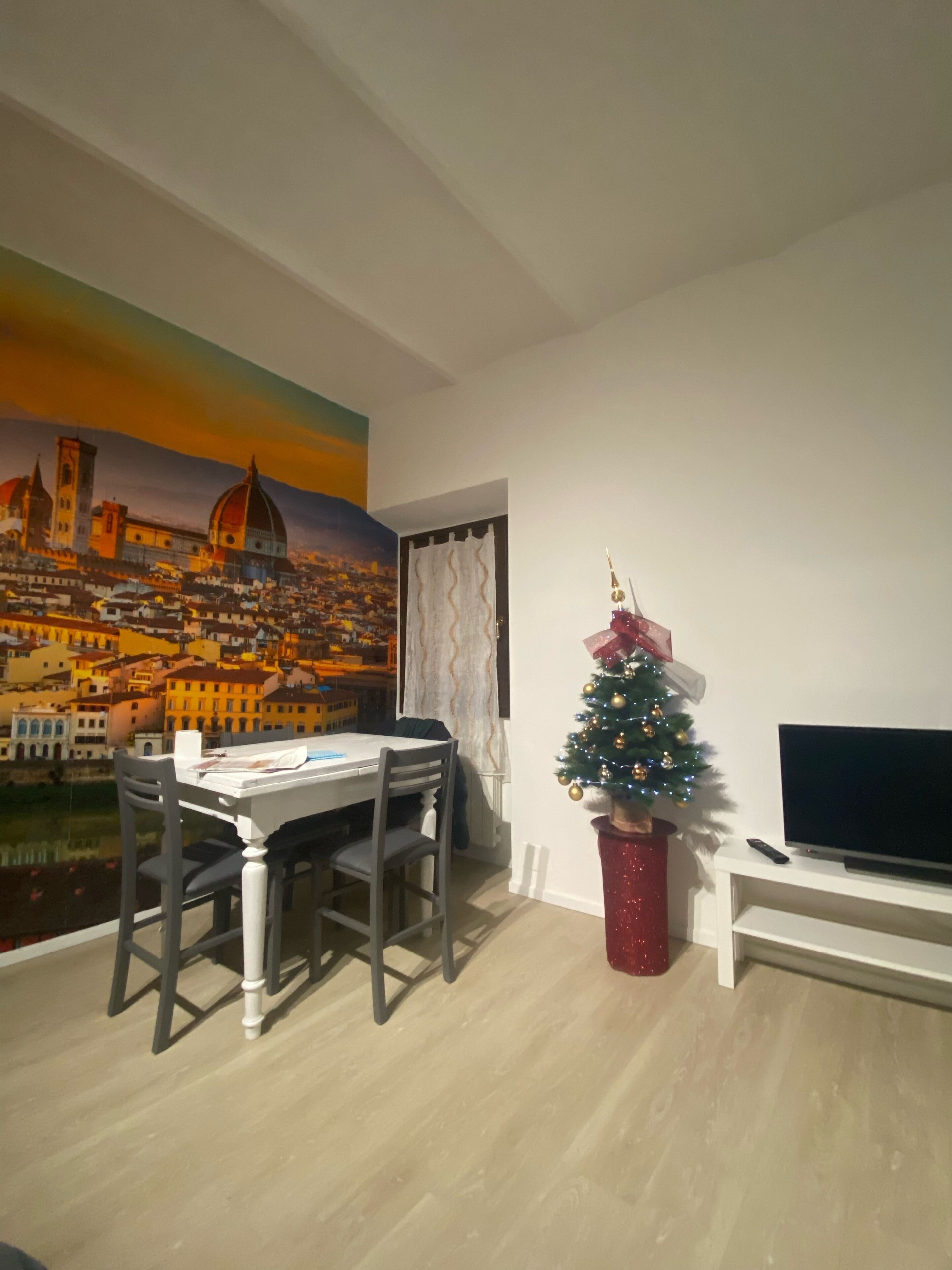 Ein Essbereich mit Tisch und Stühlen, ein kleiner Weihnachtsbaum und ein Fernseher auf einem Schrank.