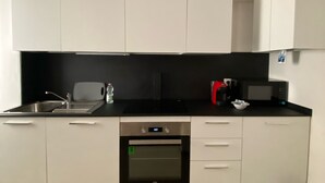 Cocina moderna con armarios blancos, encimera negra, pileta de acero inoxidable, microondas y horno.