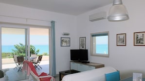 Quarto de hotel com varanda, uma cama, televisão, escrivaninha e um mapa sobre a mesa.