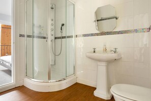 Une salle de bain avec une douche à parois de verre, un lavabo sur colonne et des toilettes.