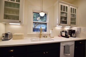 A kitchen with a built-in sink, a toaster, a coffee maker, and cabinets with glass doors.