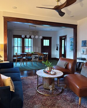 A living room with a sofa, a coffee table, and a dining area with chairs and a table.