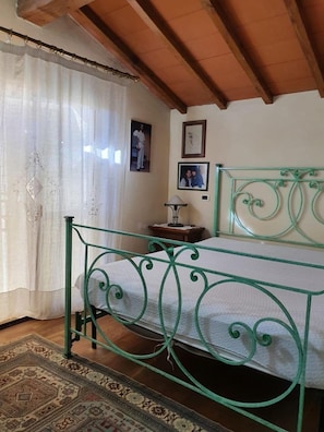 A bedroom with a green metal bed frame, a patterned rug, and a wooden ceiling. - Beautiful Villa in Versilia with Pool-Beautiful Villa in Versilia with Pool (Strettoia)