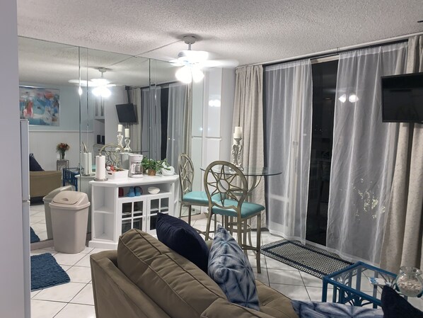 A modern living room with a sofa, a dining table, and a TV.