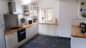 Een compacte keuken met witte kasten, een zwarte kookplaat, een magnetron en een spoelbak.