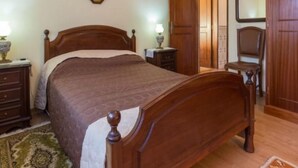 Une chambre à coucher avec un lit en bois, des tables de chevet, une commode, une chaise, une armoire et un miroir.
