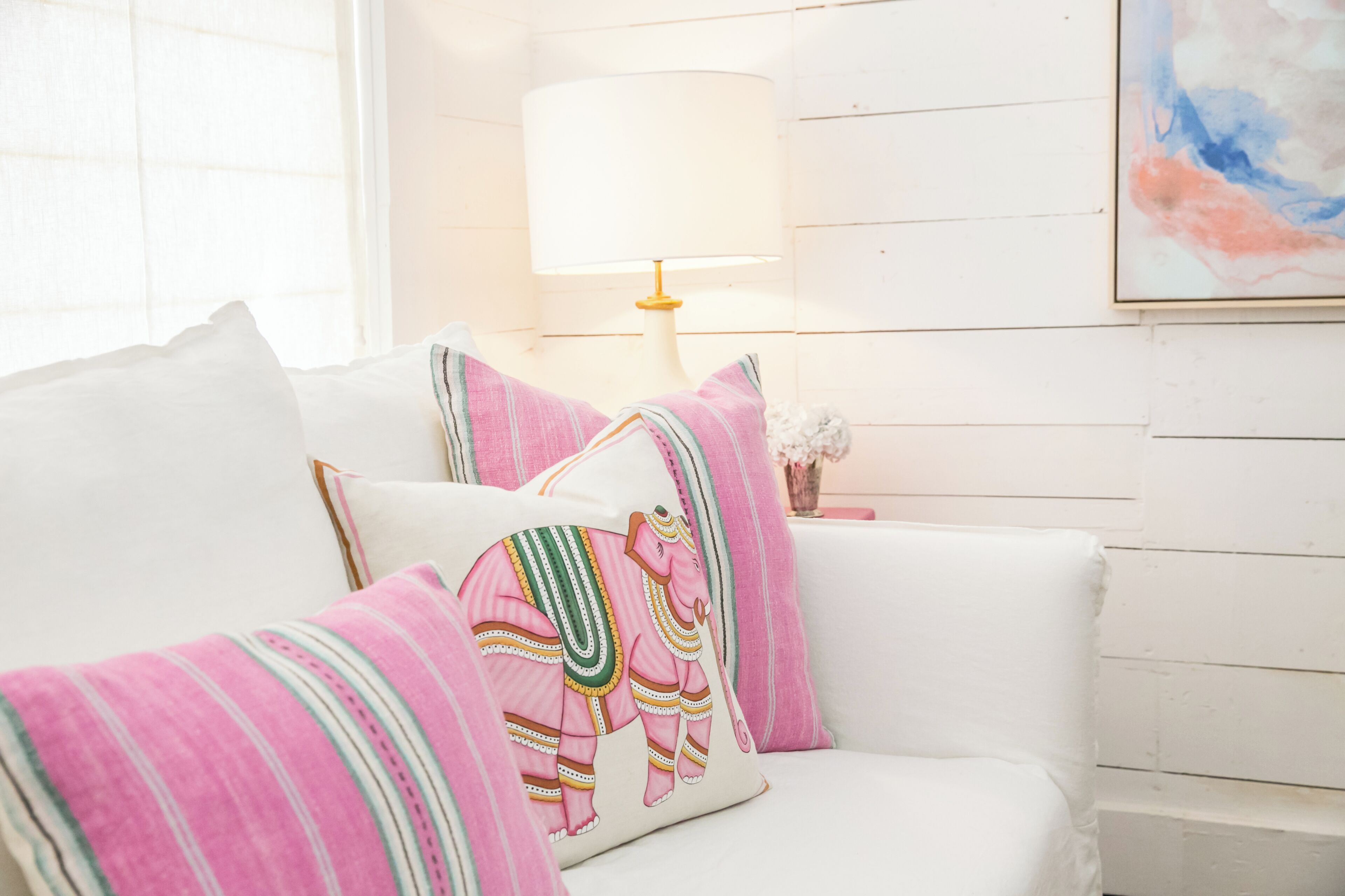 A white sofa with striped pillows and a decorative pillow with an elephant design.
