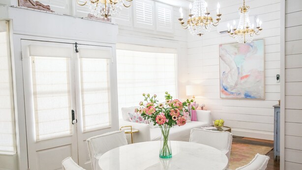 A white dining area with a round table, white chairs, a vase with flowers, and a chandelier. - "Pigs Fly" an Adorable Guest Suite in the Round Top Area  (Burton)