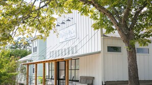 A building with a sign reading "Pigs Fly & Co. boutique and merchandise" and a wooden porch with chairs. - "Pigs Fly" an Adorable Guest Suite in the Round Top Area  (Burton)