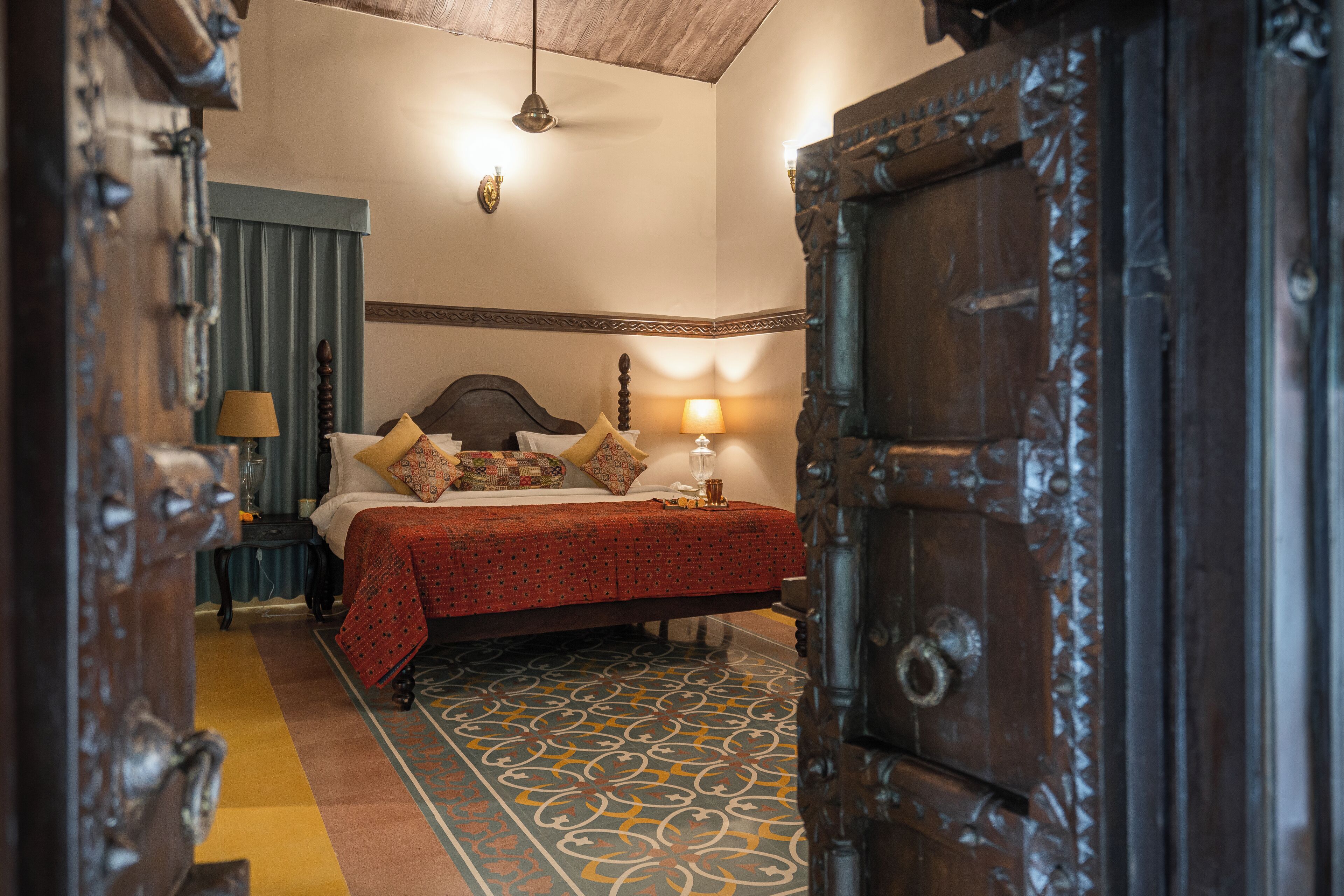 Una habitación con cama, lámpara y suelo estampado.