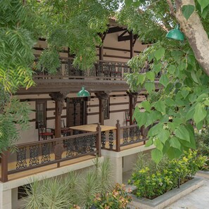 Een meerlaags gebouw met balkons, houten leuningen en een tuin met verschillende planten.