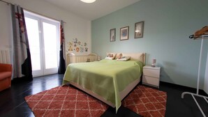 A bedroom with a bed, nightstand, and a window with curtains.