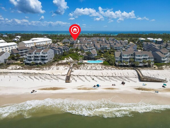 A coastal residential area with beachfront properties, a swimming pool, and a boardwalk leading to the beach.