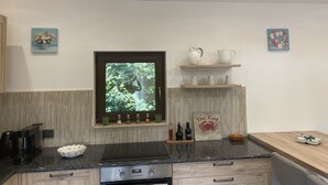 Uma cozinha moderna com forno embutido, cafeteira e uma tigela de frutas no balcão.