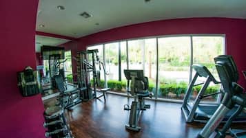 A gym with exercise equipment, large windows, and a curved ceiling.