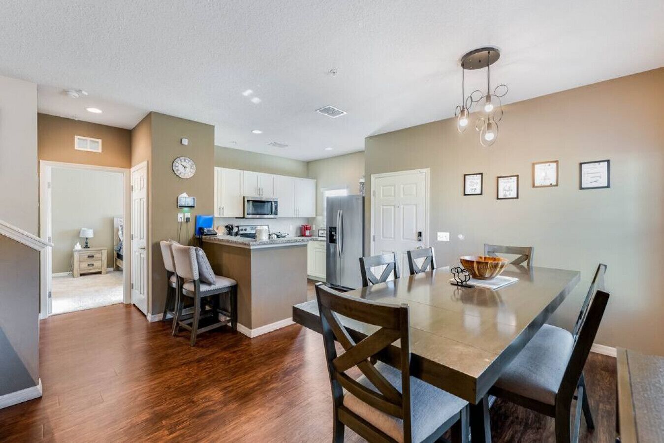A modern kitchen with white cabinets, a central island, and a dining area with a large table and chairs.