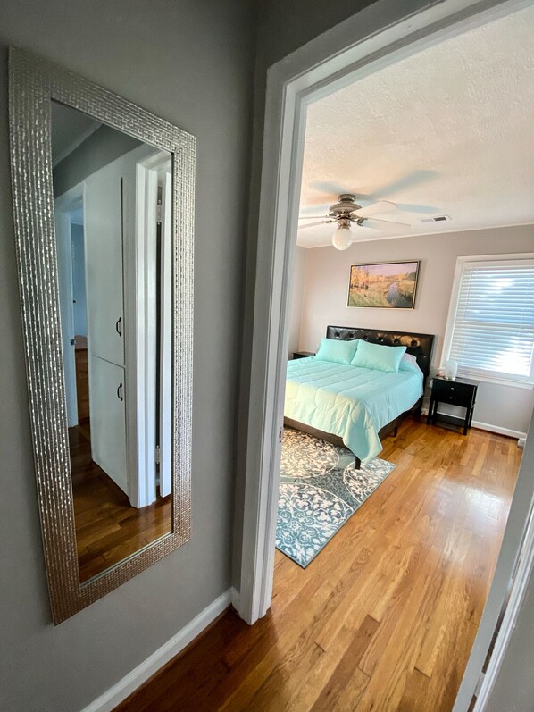 A bedroom with a bed, a ceiling fan, a window with blinds, and a door leading to another room. - Cozy Ranch Close to everything  (Merriam)