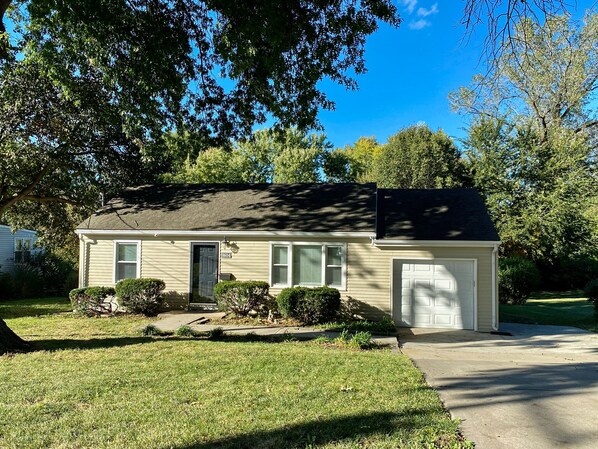 A single-story house with a dark roof, beige siding, and a front garage.