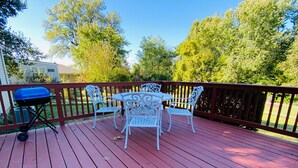 A wooden deck with a barbecue grill, a table, and four chairs. - Cozy Ranch Close to everything (Merriam)