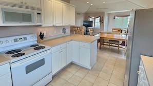 A kitchen with white cabinets, a microwave, stove, and a refrigerator. - Steps From The Beach and Minutes to The Boards - Now Includes Linens (Milton)