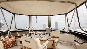 A boat's interior with a steering wheel, control panel, and two white leather seats. - Spacious & Comfy 2BR/2Bath Yacht -Toasty Heat- On Freedom Trail-Walk to Downtown (Boston)