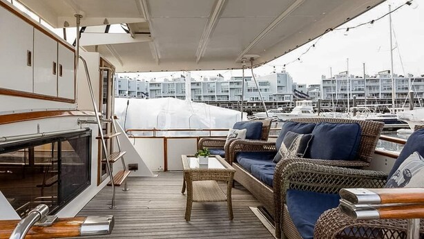 A deck with wicker furniture and a table, overlooking a marina with boats. - Spacious & Comfy 2BR/2Bath Yacht -Toasty Heat- On Freedom Trail-Walk to Downtown (Boston)